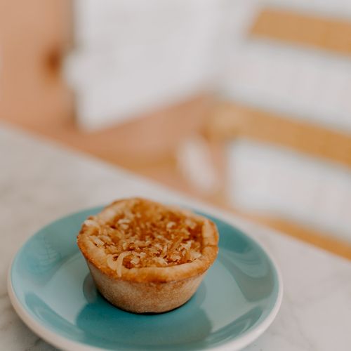 A small crumbly pie on a blue plate, placed on a marble surface with a blurred background.